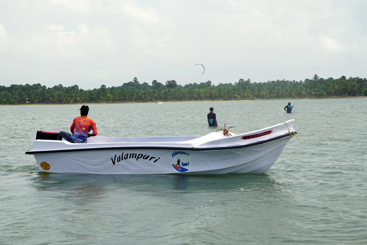 Kitesurfer riding flat water on Kalpitiya Lagoon near a support boat
