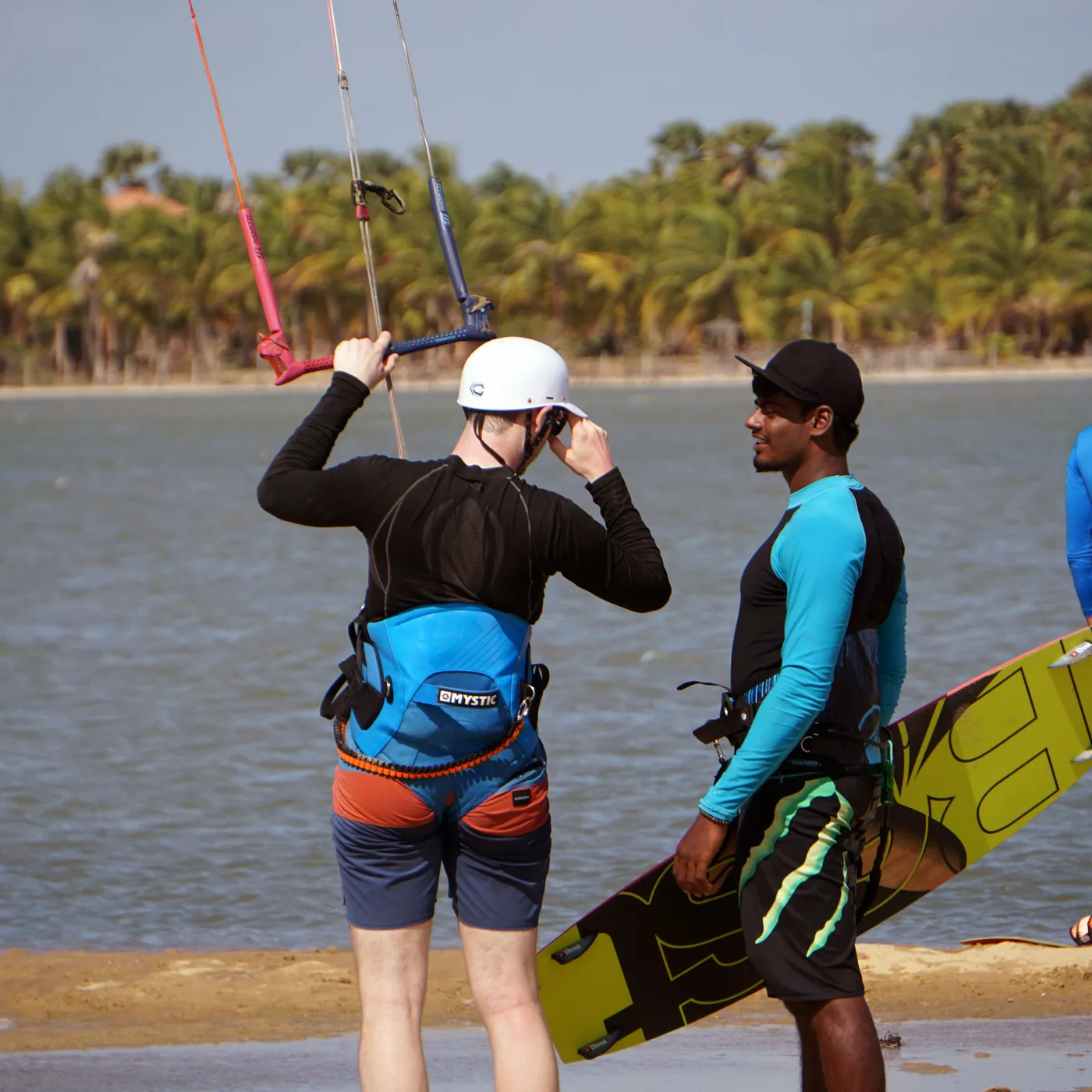 Instructor and student checking helmet and safety gear at the water's edge, Kalpitiya